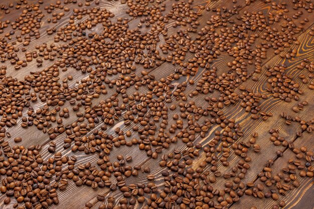 Grains de café torréfiés répartis sur fond plein cadre en bois avec perspective linéaire