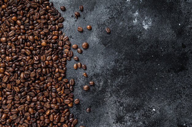 Grains de café torréfiés sur table rustique sur table noire. Vue de dessus.