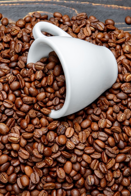 Grains de café torréfiés et tasse sur fond de bois