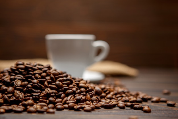 Grains de café torréfiés et tasse sur fond de bois