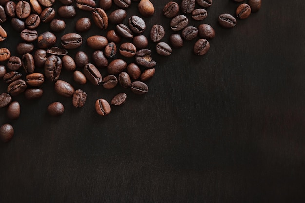 Grains de café torréfiés sur une vue de dessus de table sombre en bois