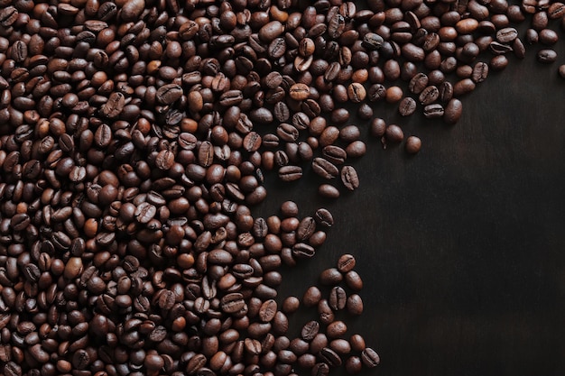 Grains de café torréfiés sur une vue de dessus de table sombre en bois