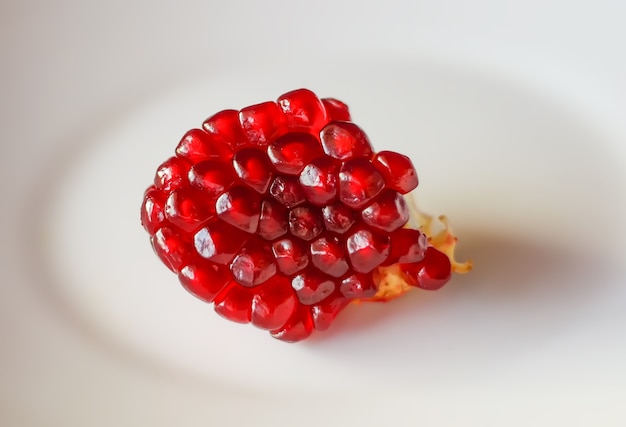 Grains de grenade mûrs rouges sur fond blanc.