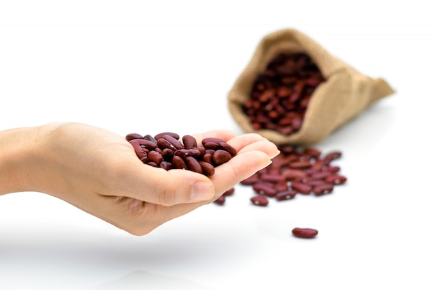 Grains haricots rouges à la main un sac sur un blanc isolé