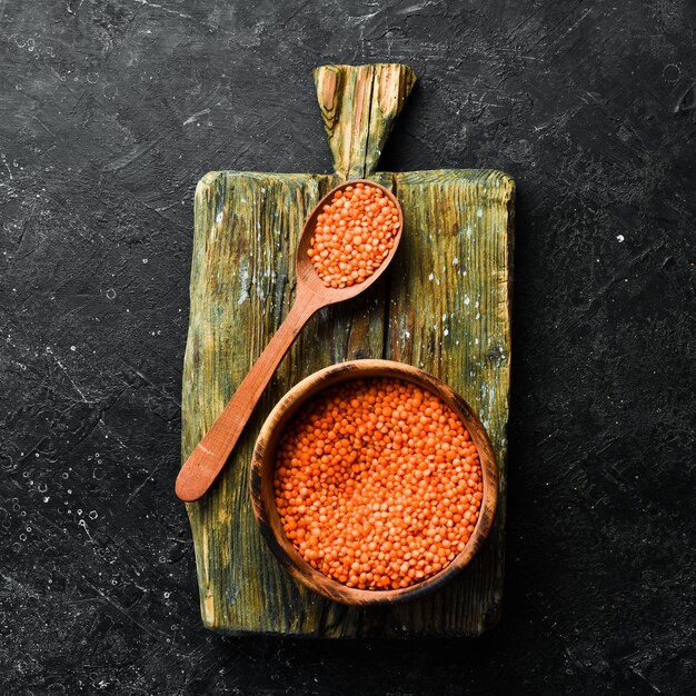 Grains de lentilles rouges biologiques dans un bol en bois sur fond de pierre Alimentation saine