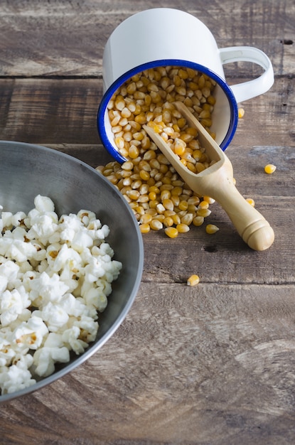 Grains de maïs et pop-corn sur fond en bois.