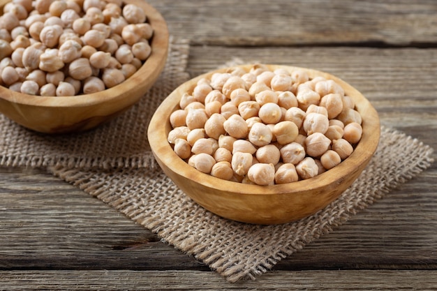 Grains de pois chiches crus dans un bol sur une table rustique en bois