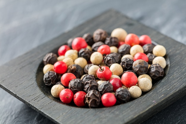 Grains de poivre colorés dans un bol en bois