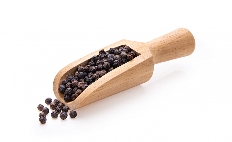 Photo grains de poivre dans une cuillère en bois isolé sur fond blanc