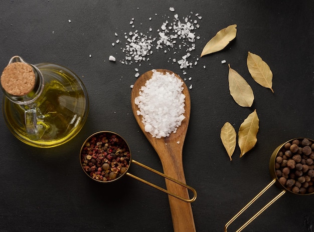 Grains de poivre et d'huile d'olive dans une bouteille sur une table noire