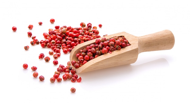 Grains de poivre rouge en bois sur blanc