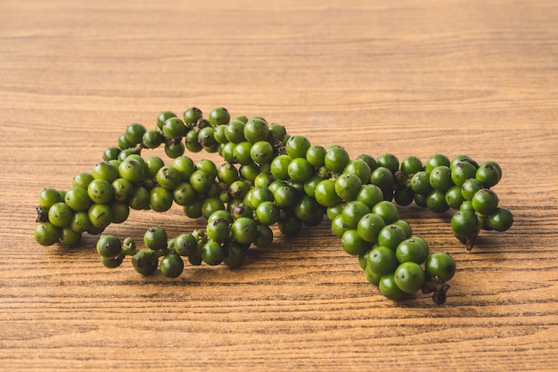 Grains de poivre vert sur fond en bois.