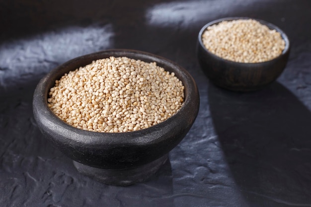 Grains de quinoa avec cuillère et bol sur fond noir