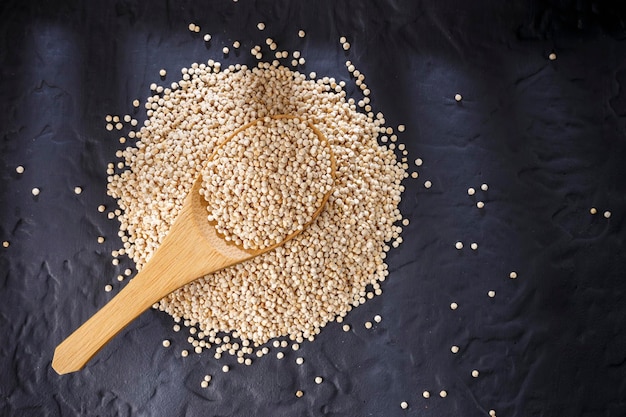 Grains de quinoa avec cuillère et bol sur fond noir