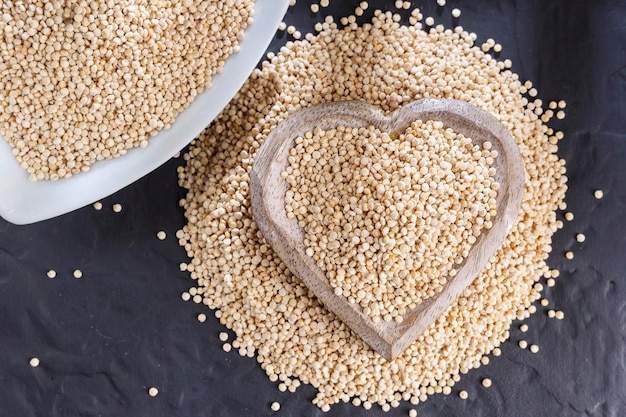 Grains de quinoa avec cuillère et bol sur fond noir