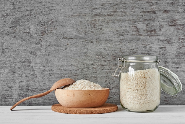 Grains de riz dans un bol en bois et bocal en verre