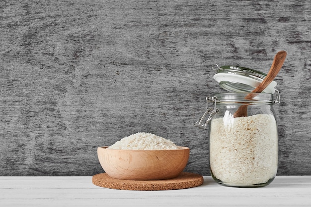 Grains de riz dans un bol en bois et un bocal en verre