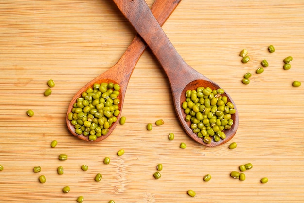 Gramme vert ou haricot mungo dans une cuillère en bois sur fond de bois.