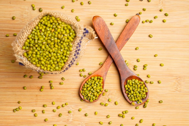 Photo gramme vert ou haricot mungo dans une cuillère en bois sur fond de bois.