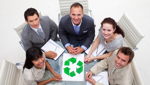 Grand angle de l&#39;équipe des affaires souriant tenant un symbole de recyclage