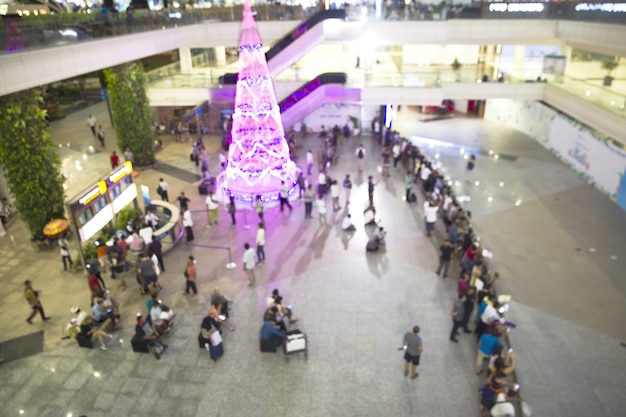 Grand arbre de noël à l'aéroport avec des personnes floues qui arrivent ou partent pour le week-end