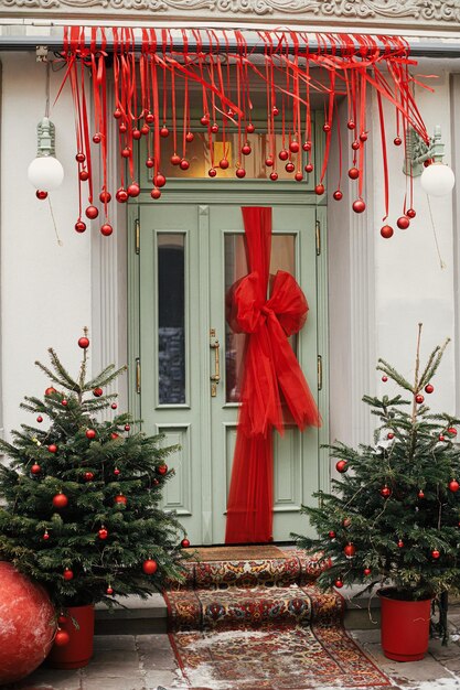 Grand arc de Noël élégant sur les portes vertes boules rouges et sapin à l'extérieur du bâtiment festif Décor de Noël moderne dans la rue de la ville Vacances d'hiver en Europe Joyeux Noël