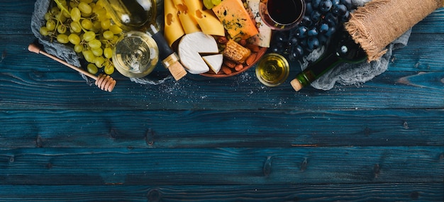 Un grand assortiment de fromages vin miel noix et épices sur une table en bois bleue Vue de dessus Espace libre pour le texte