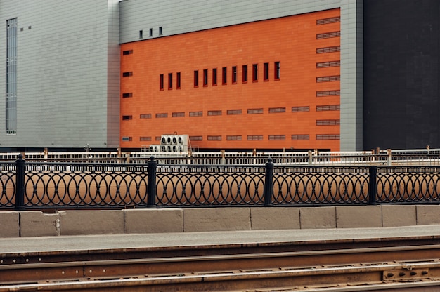 Un grand bâtiment gris avec un mur orange. Ville colorée. Vide.