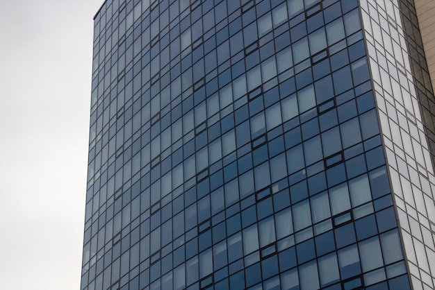 Grand bâtiment moderne en verre contre un ciel gris