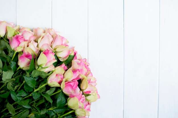 grand bouquet de roses avec des pétales roses et vert sur fond de bois blanc
