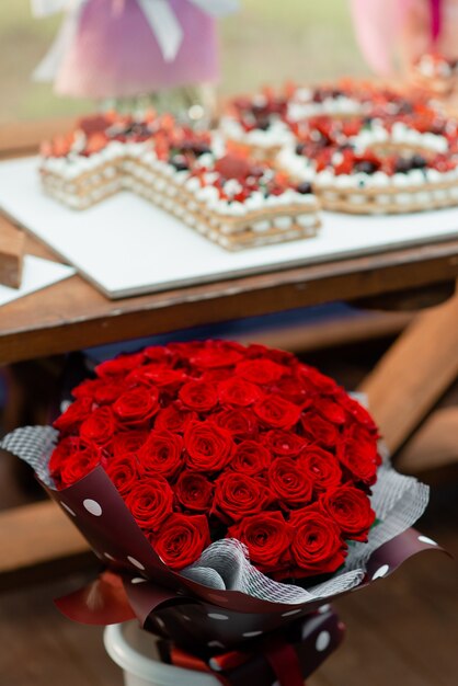 Un grand bouquet de roses rouges sur le fond d'un gâteau de fête avec un gâteau.