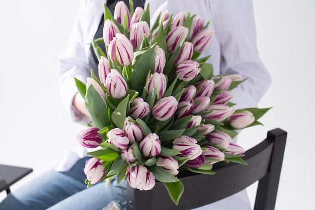 Un grand bouquet de tulipes de différentes couleurs entre les mains d'une femme