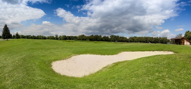 Grand bunker de sable sur terrain de golf avec herbe verte parfaite