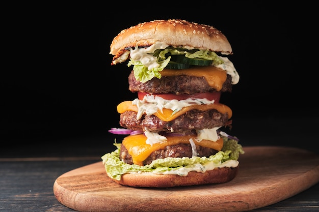 Grand burger grillé avec des légumes sur une planche de bois