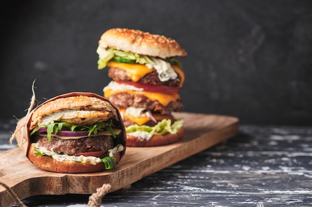 Grand burger grillé avec des légumes sur une planche de bois