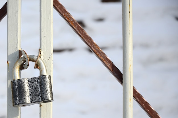 Un grand cadenas gris est suspendu à une porte en métal