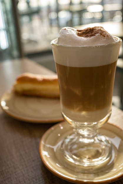 Grand café en verre cappuccino avec un pain au sucre à la crème dans un restaurantPetit-déjeuner matinal ou concepts après le déjeuner