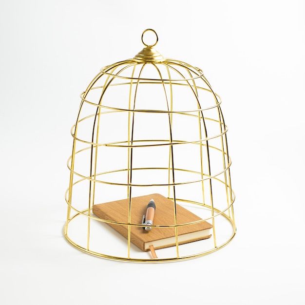 Grand cahier et stylo de cage à oiseaux dorés sur le concept de fond blanc