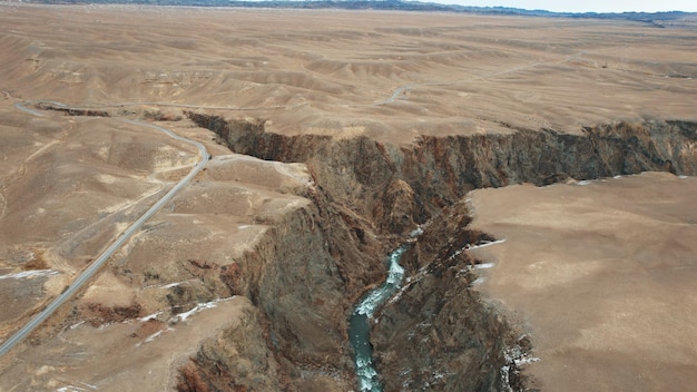 Le Grand Canyon dans la steppe avec la rivière émeraude. Une fissure dans le sol avec des pierres noires