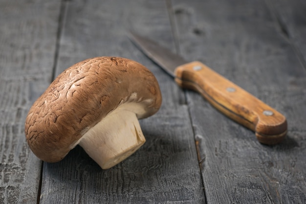 Un grand champagne Royal et un couteau sur une table en bois noir. La nourriture végétarienne. Champignons cultivés artificiellement.