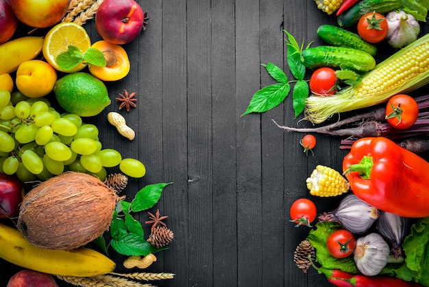 Grand choix de légumes crus et de fruits sur une table en bois noire Espace libre pour votre texte Vue de dessus