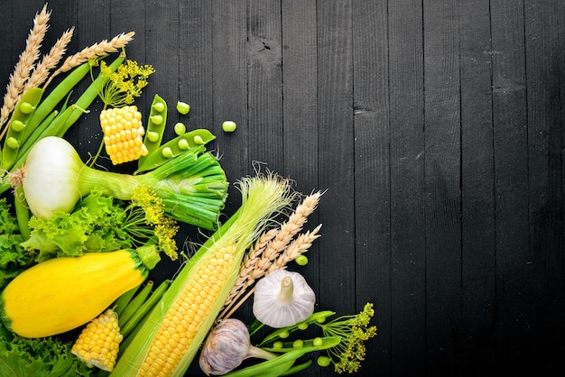 Un grand choix de légumes frais crus verts de laitue de courgettes de maïs Sur un fond en bois noir Vue de dessus Espace libre pour votre texte