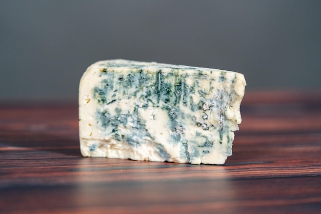 Grand coin de fromage bleu sur un fond en bois foncé.