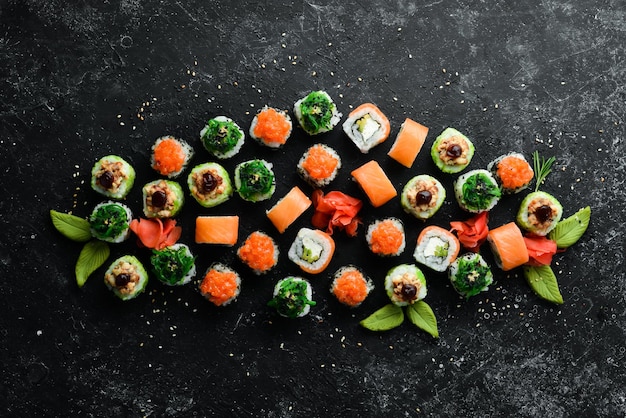 Grand ensemble de morceaux de rouleaux de sushi sur fond de pierre noire Vue de dessus Espace libre pour votre texte