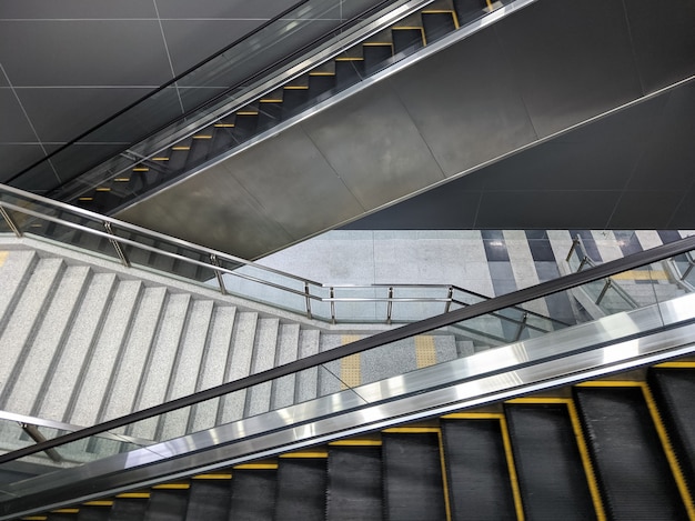 Le grand escalier vide et le nouvel escalator jumeau fonctionnent jusqu'au plancher du quai de la station de métro, testant la fonctionnalité avant le service réel, vue de face pour l'arrière-plan.