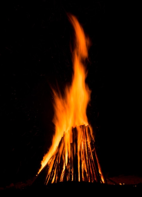 Grand feu de joie contre le ciel nocturne sombre. Flammes de feu sur fond noir