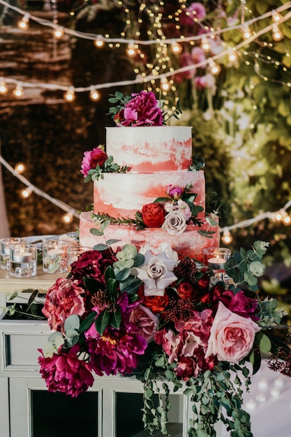 Grand gâteau de mariage décoré de fleurs rouges.