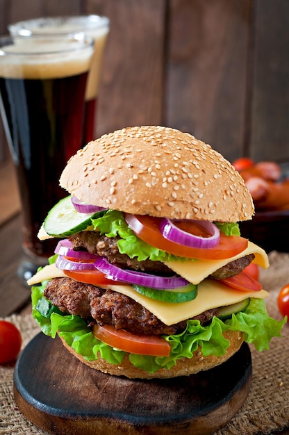 Grand hamburger juteux avec des légumes et du bœuf sur un fond en bois dans un style rustique