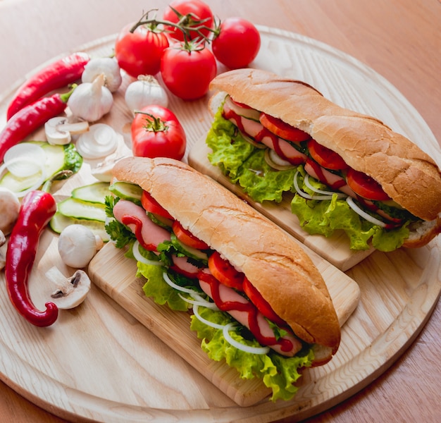 Grand hot-dog avec des légumes sur la table.