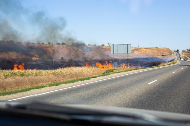 Un grand incendie sur le bord de la route par une journée d'été sèche Urgence et risque d'incendie